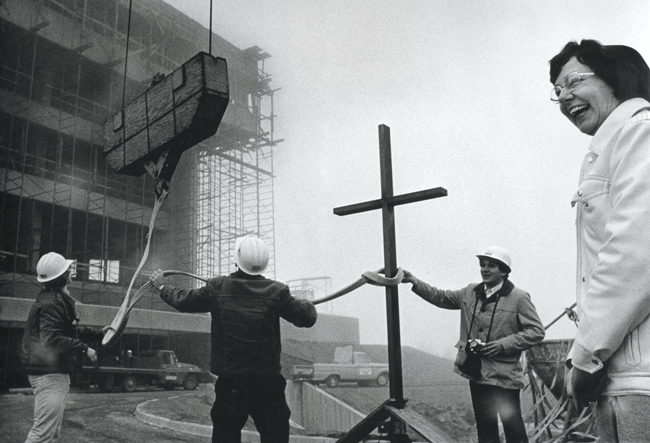 Sister Catherine standing next to cross being placed on top of St. Charles Bend