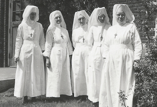 Black and white photo of five nuns standing outside in the sun