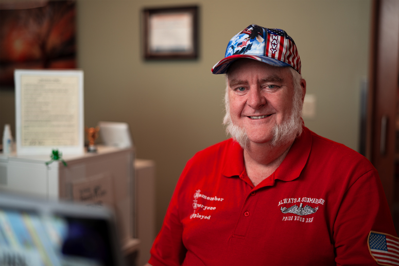 Man in red shirt with white hair wearing a hat