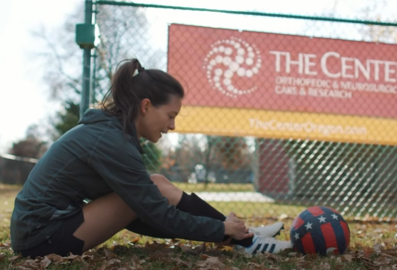 girl tying her shoes in a soccer field