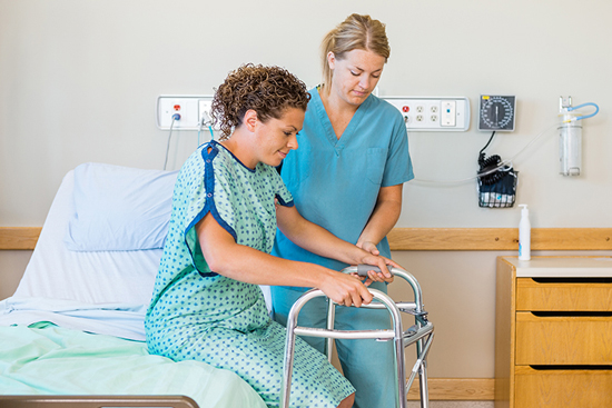 nurse helping patient up from hospital bed