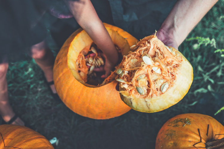 person scooping guts out of a pumpkin