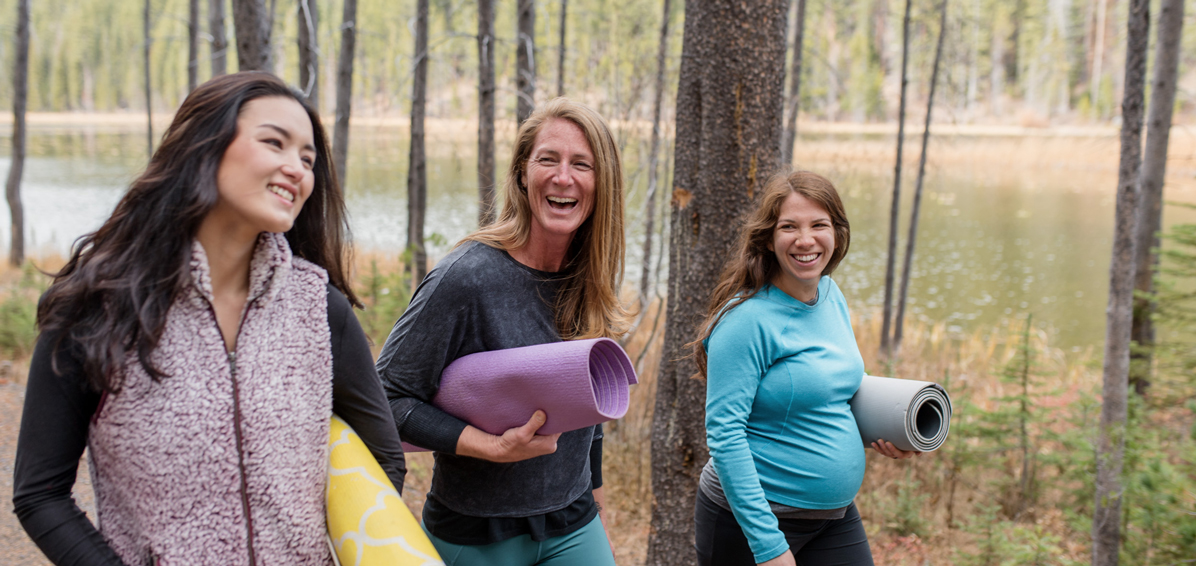 Women walking through woods with yoga mats