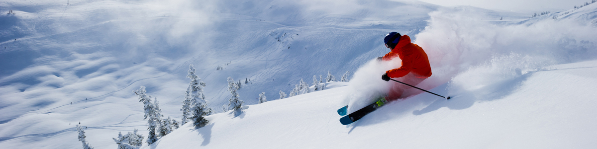 alpine skier in red skiing down a mountain