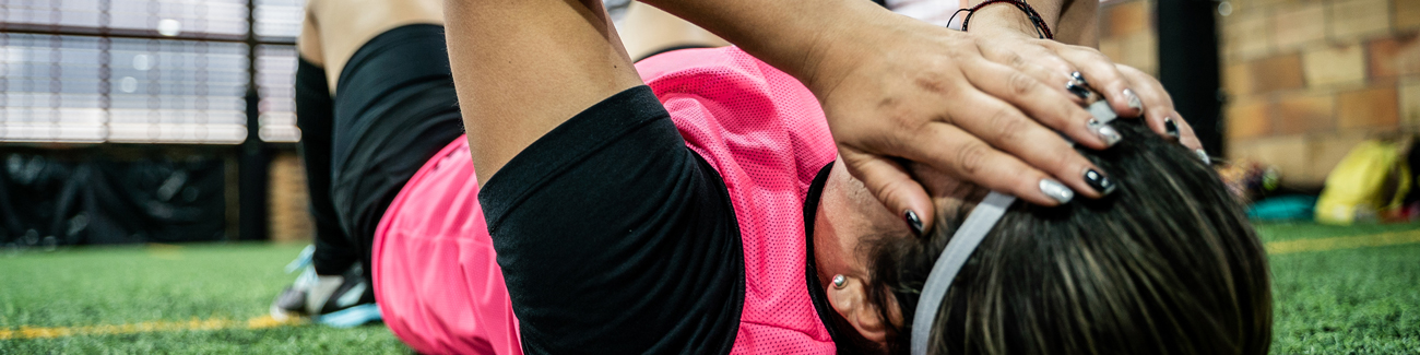 female athlete laying on ground holding head