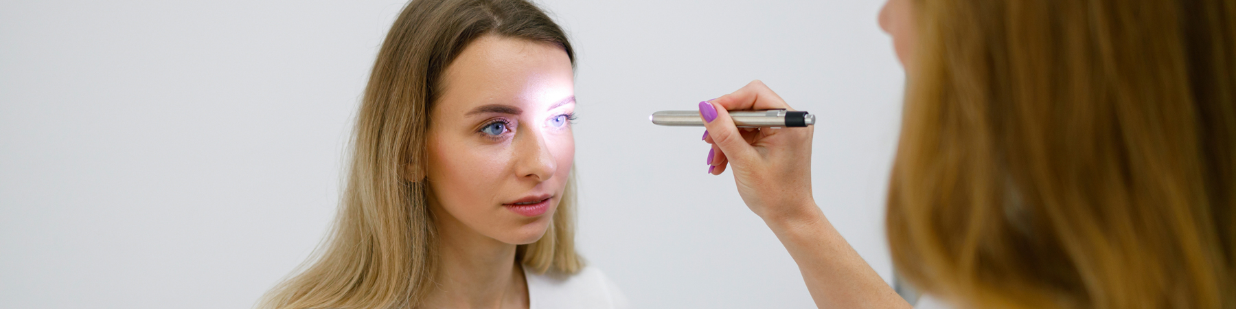 woman getting concussion exam using light in eyes