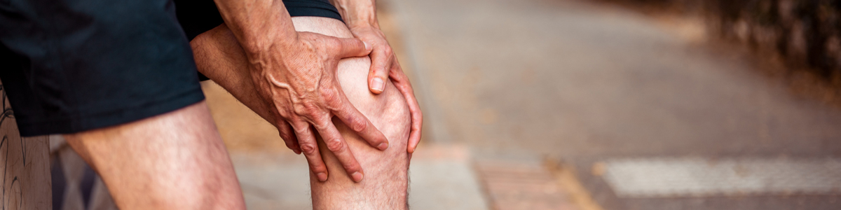 man holding knee while running outside