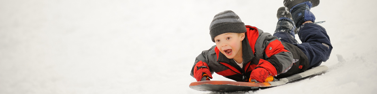 little boy sledding down a snowy hill