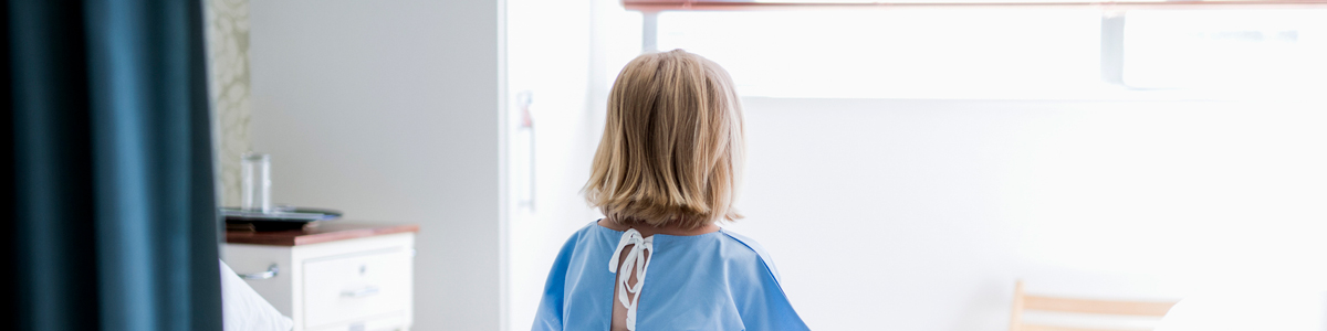 child sitting on hospital bed looking out window