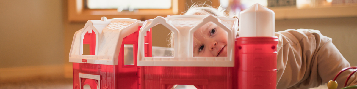 little girl playing with toy barn