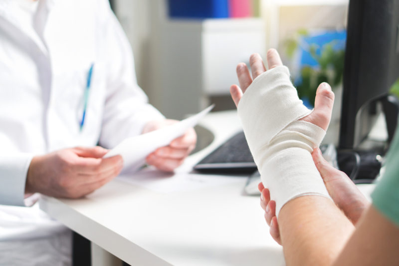 Patient with bandage on wrist walking to doctor